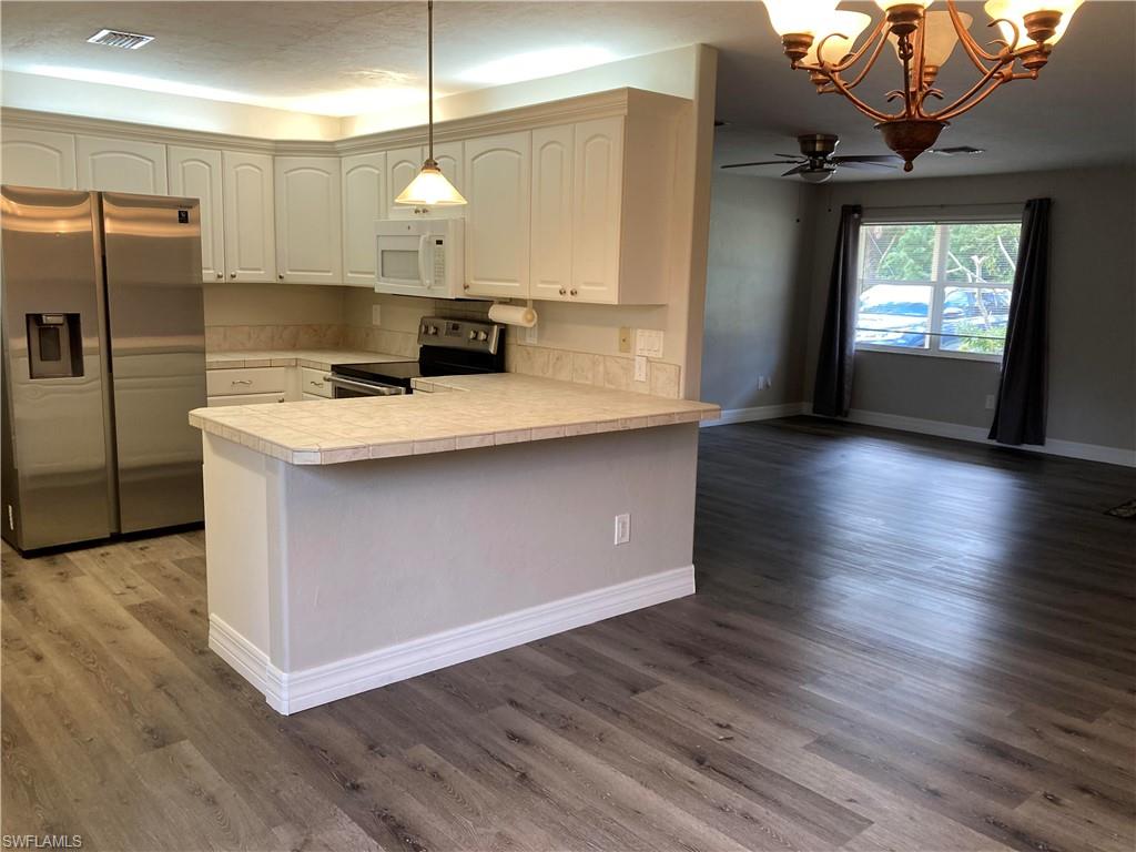 203 Esther Street Naples, FL 34104 - Photo 10 of 33 Kitchen featuring stainless steel appliances, light countertops, light wood-style flooring, and hanging lights