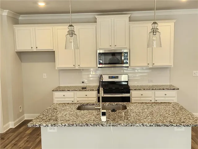 a kitchen with stainless steel appliances granite countertop a stove a sink and a microwave
