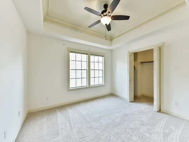 an empty room with a ceiling fan and carpet