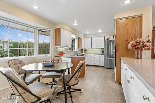 a kitchen with a dining table chairs and refrigerator