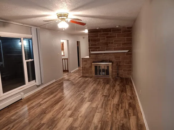 a view of an empty room with wooden floor and a window