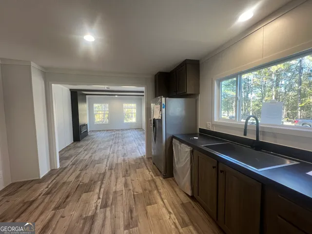 a kitchen with sink a refrigerator and wooden floor