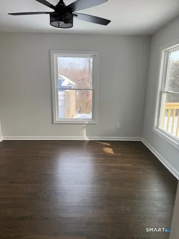 an empty room with wooden floor and windows