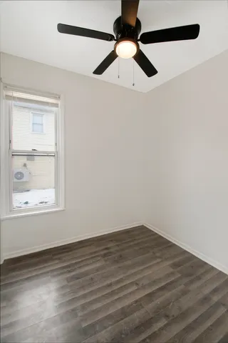 an empty room with a window and a ceiling fan
