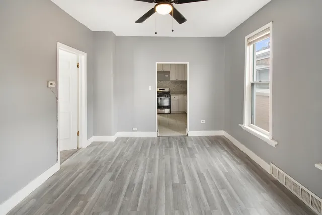 an empty room with wooden floor cabinet and windows