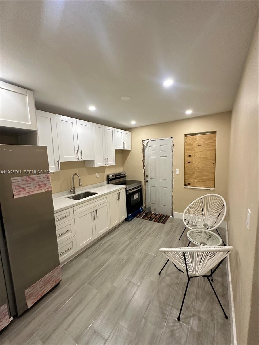 234 Northeast 55th Terrace Miami, FL 33137 - Photo 5 of 22 a kitchen with a refrigerator and white cabinets