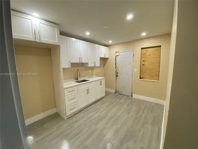a view of a kitchen with white cabinets and wooden floor