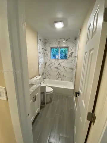 a bathroom with a sink and mirror with bathtub
