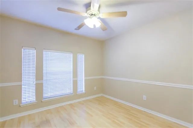 an empty room with windows and fan