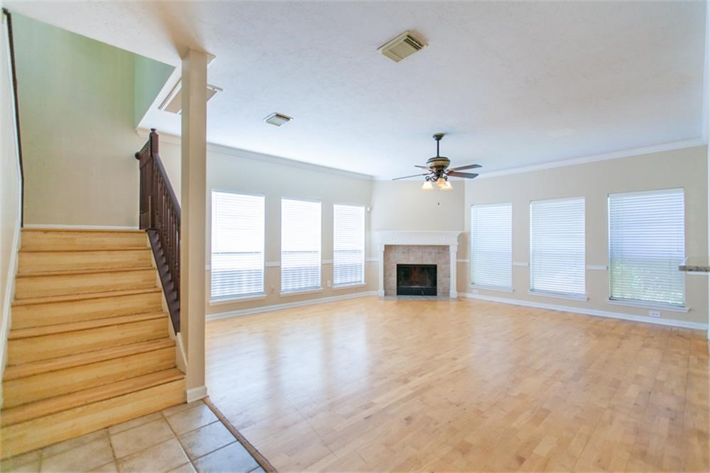 13630 Country Green Court Houston, TX 77059 - Photo 5 of 30 a view of an empty room with fireplace ceiling fan and windows