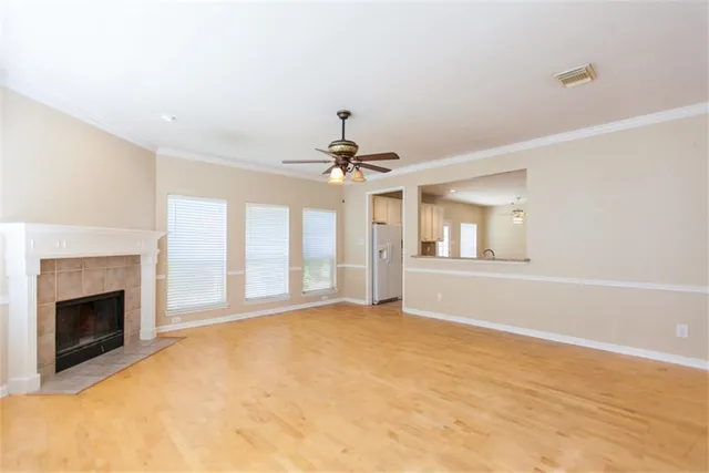 a view of an empty room with chandelier fan and fire place