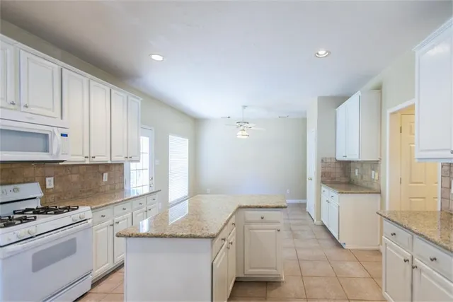 a kitchen with granite countertop a sink stainless steel appliances and white cabinets
