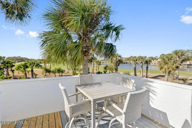 a patio with a table and chairs under palm trees