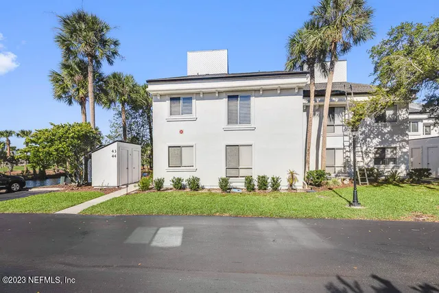 a view of a white house with a yard and palm trees
