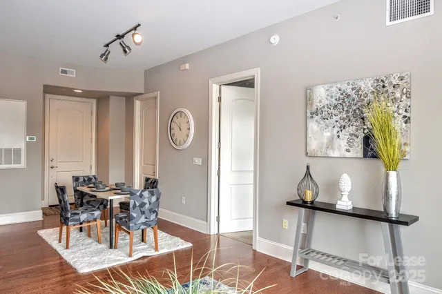 a kitchen with stainless steel appliances granite countertop a refrigerator a stove top oven a dining table and chairs with wooden floor