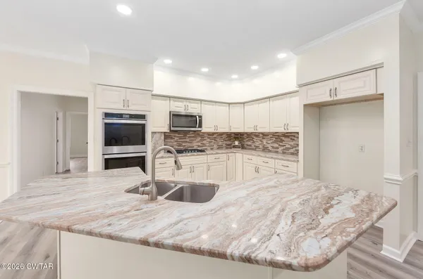 a kitchen with stainless steel appliances kitchen island granite countertop a sink and a refrigerator