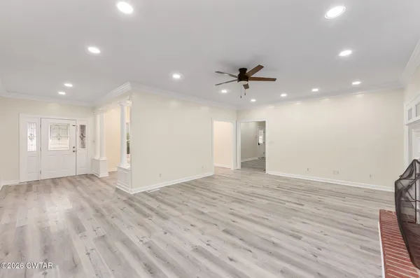 a view of an empty room with wooden floor and a ceiling fan