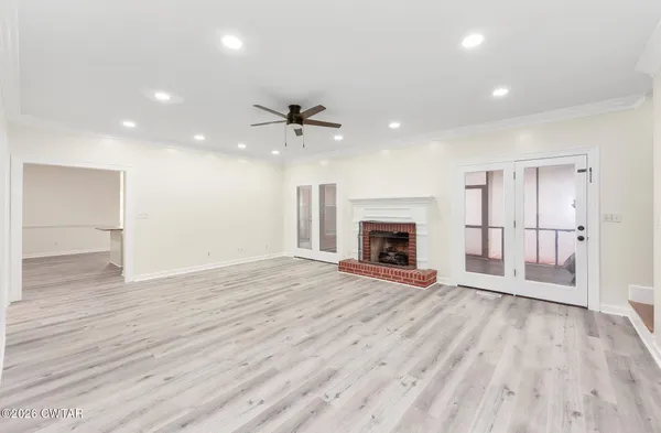 a view of an empty room with wooden floor fireplace and a window