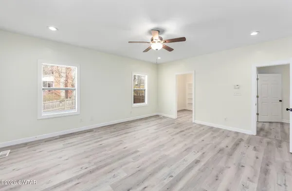 a view of empty room with wooden floor and fan