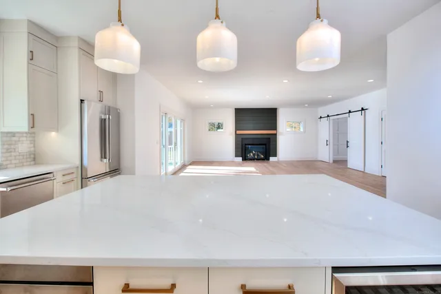 a large white kitchen with a sink and chandelier