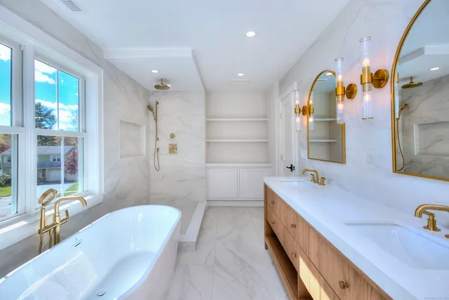 a spacious bathroom with a double vanity sink a mirror a bathtub and next to a window
