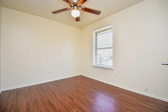 an empty room with a window and wooden floor