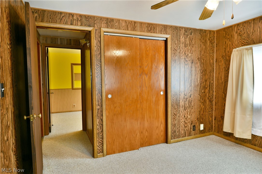 878 Ridge Road Vienna, OH 44473 - Photo 48 of 50 Unfurnished bedroom featuring a closet, wood walls, light colored carpet, and a ceiling fan