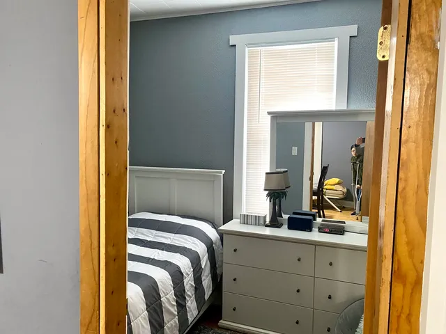 a bedroom with a bed and a dresser next to a window
