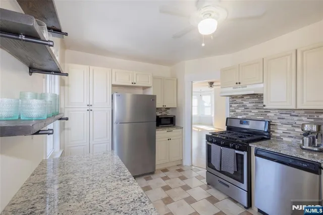 a kitchen with stainless steel appliances granite countertop a refrigerator a sink a stove a microwave and island