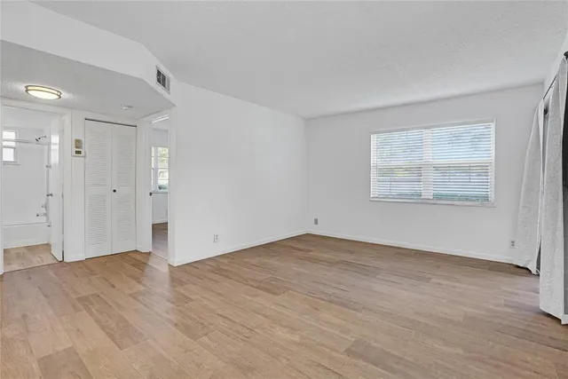 a view of empty room with wooden floor and window