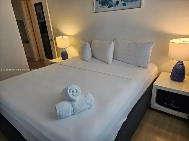 a bedroom with a bed and a potted plant on the dresser