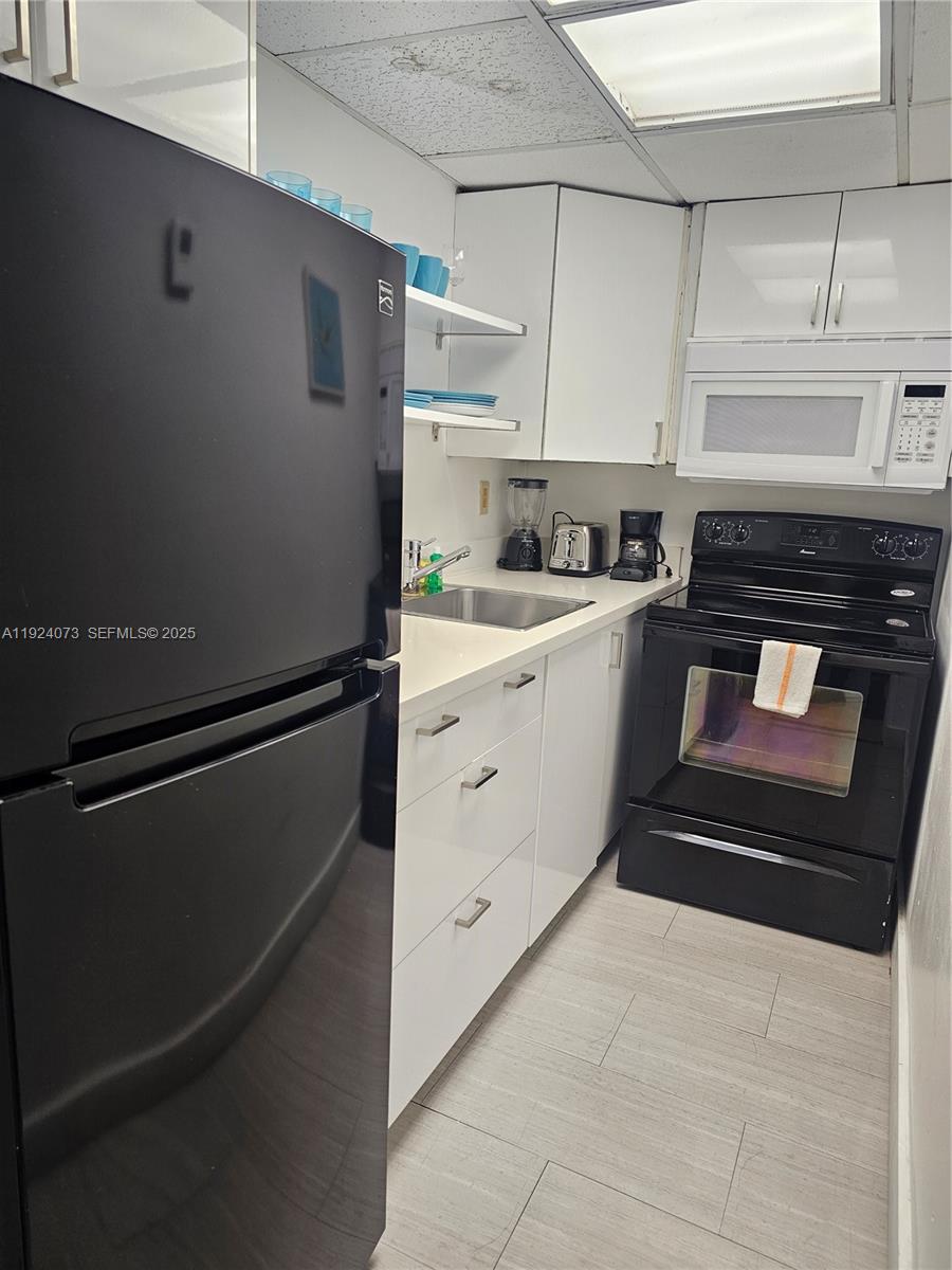 750 Collins Avenue, Unit 201 Miami Beach, FL 33139 - Photo 2 of 39 a kitchen with a stove and white cabinets