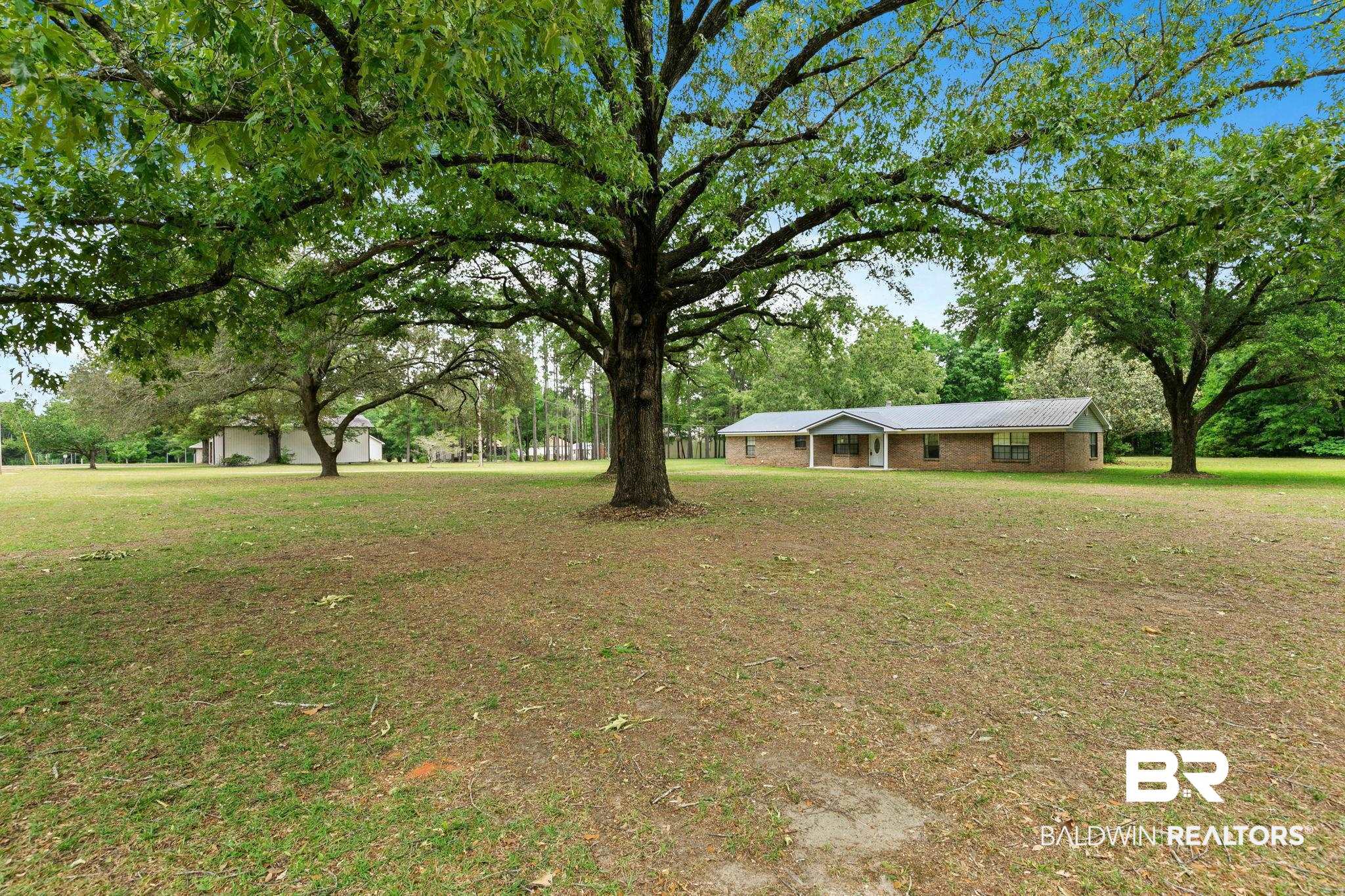 13653 Roberts Road Loxley, AL 36551 - Photo 5 of 33 Expansive green space featuring established trees and a distant brick-front residence with a covered entry