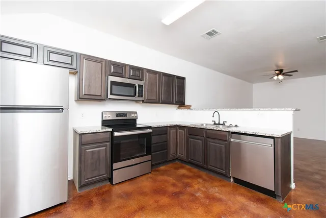 a kitchen with granite countertop stainless steel appliances and wooden cabinets