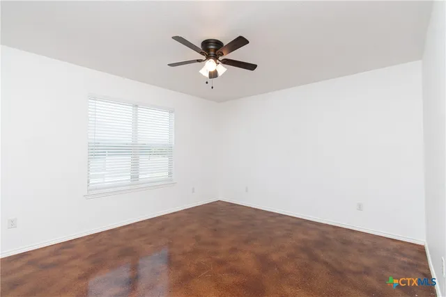 an empty room with a window and a fan