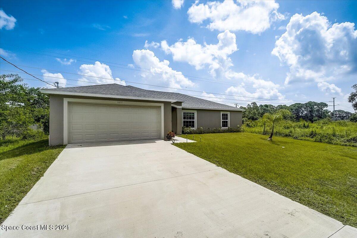 1459 Saxony Road Southwest Palm Bay, FL 32908 - Photo 2 of 38 a front view of a house with a garden and yard