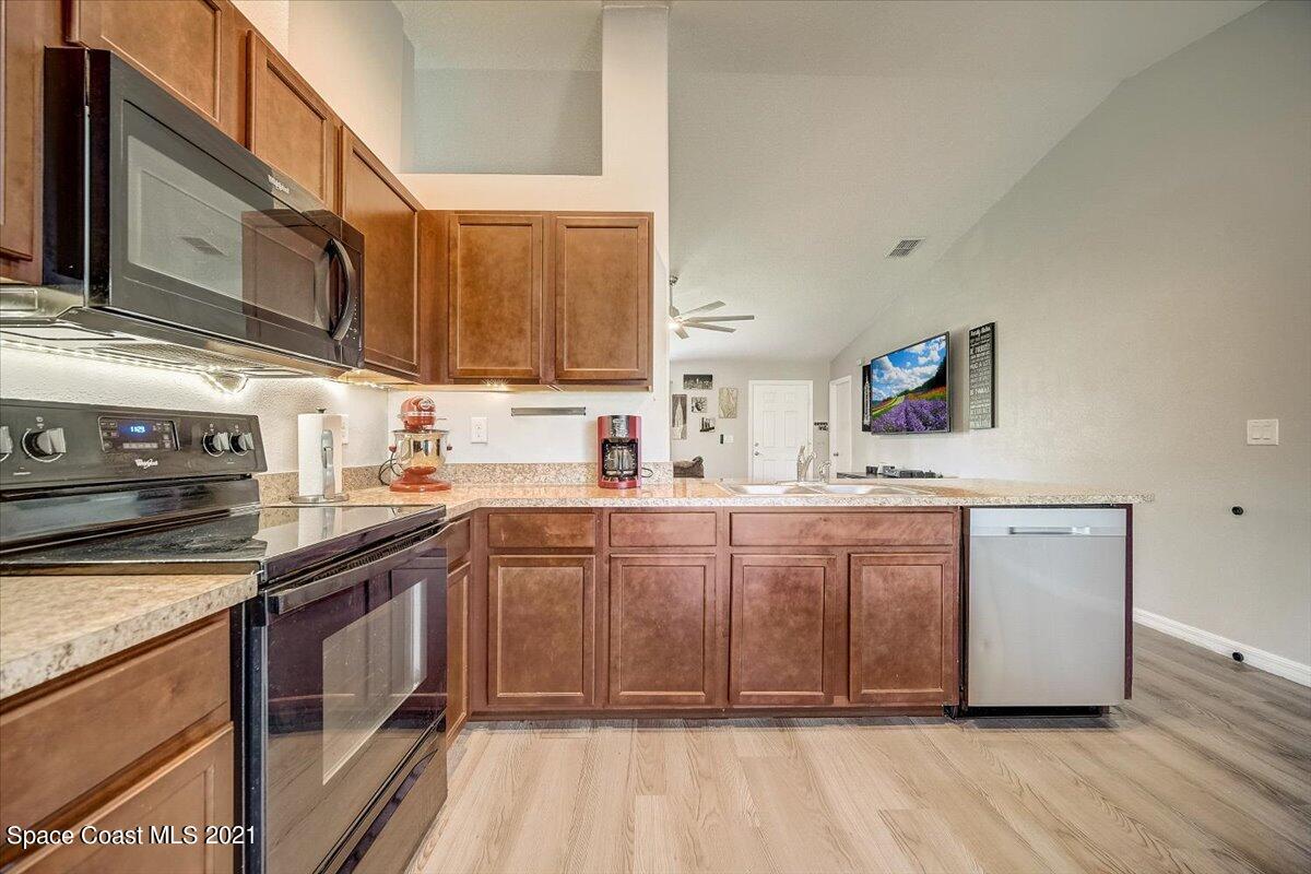 1459 Saxony Road Southwest Palm Bay, FL 32908 - Photo 12 of 38 a kitchen with stainless steel appliances granite countertop a sink a stove and a microwave oven with cabinets