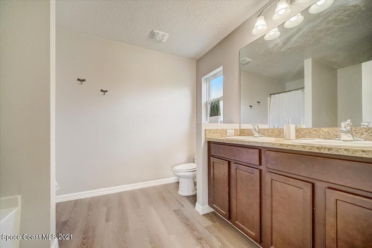 1459 Saxony Road Southwest Palm Bay, FL 32908 - Photo 28 of 38 a bathroom with a granite countertop sink a toilet and a mirror