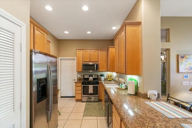 a kitchen with stainless steel appliances granite countertop a refrigerator and a stove top oven