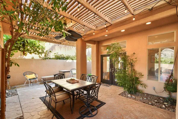 a patio with table and chairs and potted plants