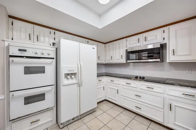 a kitchen with granite countertop white cabinets and white appliances