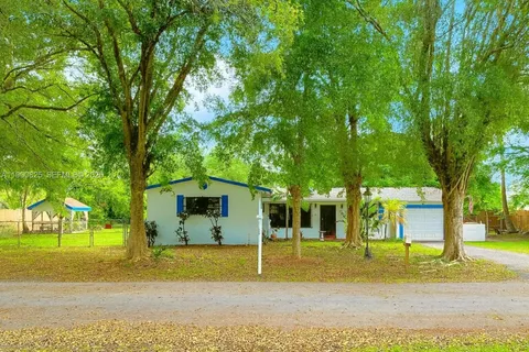 a view of a big house with large trees and plants