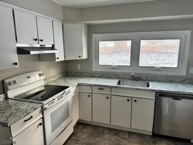 a kitchen with appliances cabinets a sink and a window
