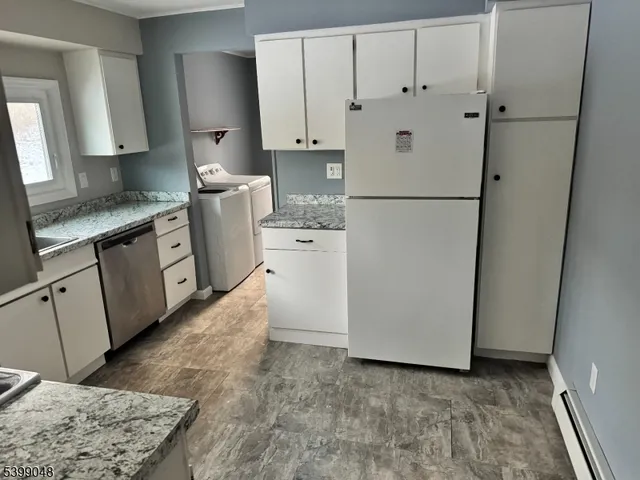 a kitchen with white cabinets and refrigerator