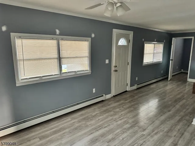 an empty room with wooden floor and windows