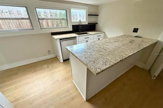 a kitchen with granite countertop sink and natural light
