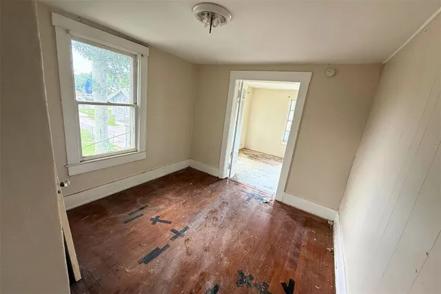 an empty room with wooden floor and windows