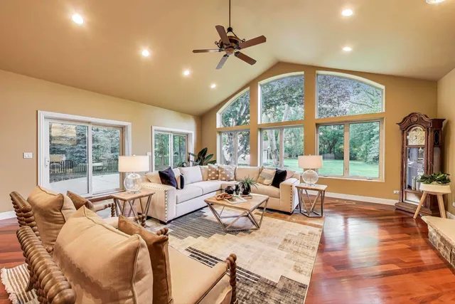 a living room with furniture large windows and wooden floor