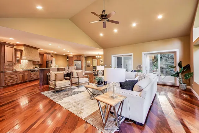 a living room with lots of furniture kitchen view and a wooden floor