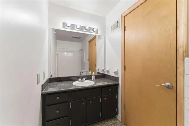 a bathroom with a granite countertop sink and a mirror